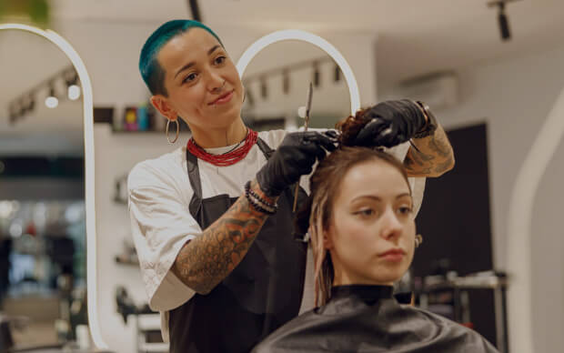 Hair stylist cutting a client’s hair with scissors in a salon