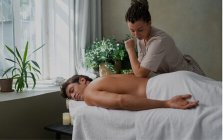 Massage therapist giving a back massage to a client lying on a treatment table