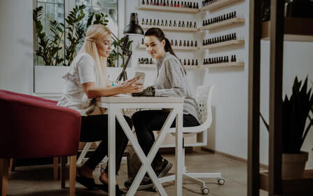 Close-up of a manicurist applying nail polish to a client’s nails