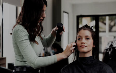 Hair stylist cutting a client’s hair with scissors in a salon
